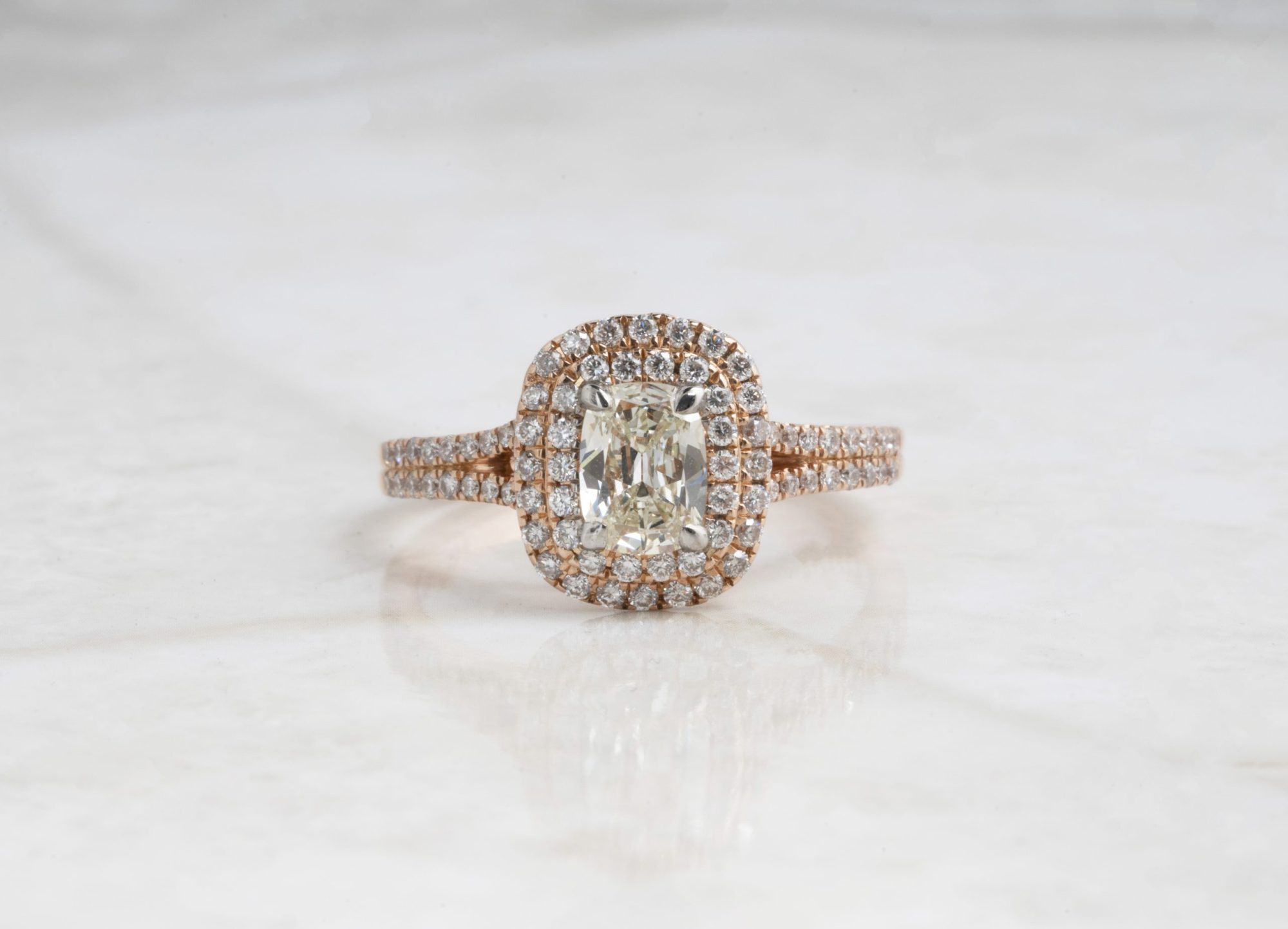 Yellow gold engagement ring centered with a diamond surrounded by a diamond double halo and diamonds in the band.