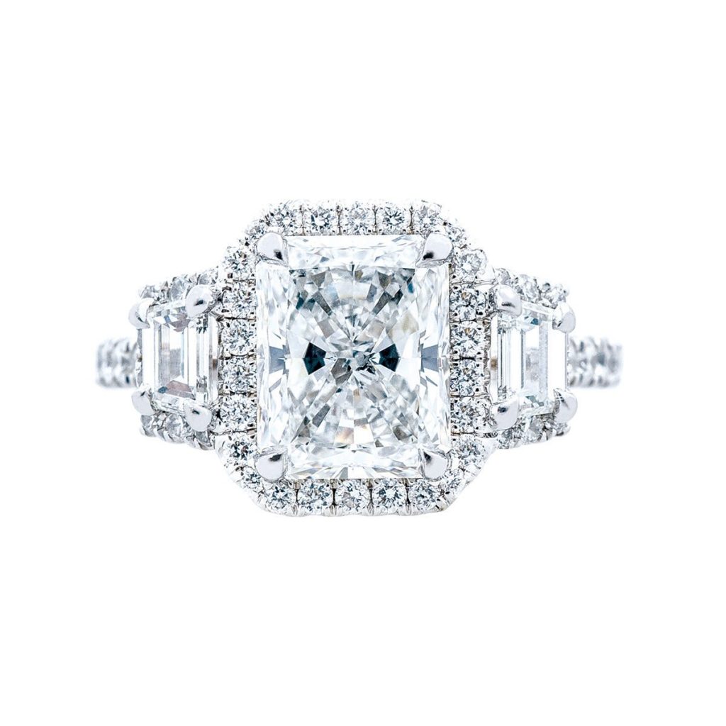 White gold three-stone diamond engagement ring with diamond haloes.