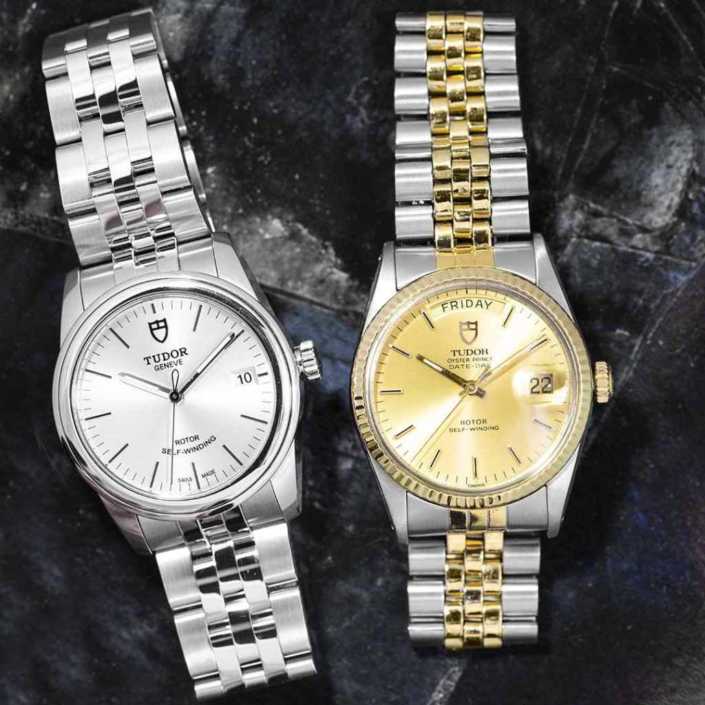 Two pre-owned Tudor watches, one in stainless steel and one in stainless steel and yellow
gold, on a black marble table.