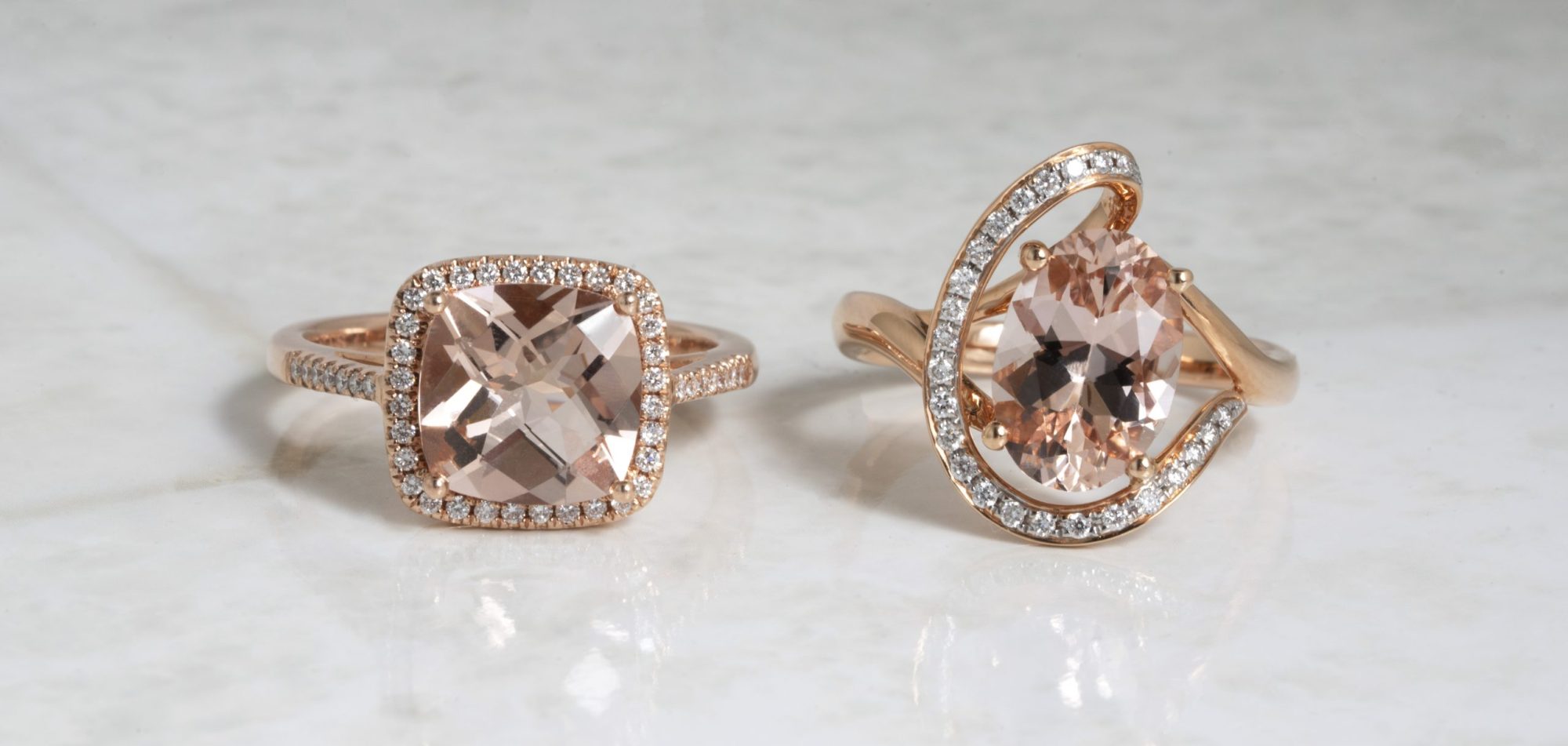 Two yellow gold engagement rings set with morganite surrounded by diamond haloes.