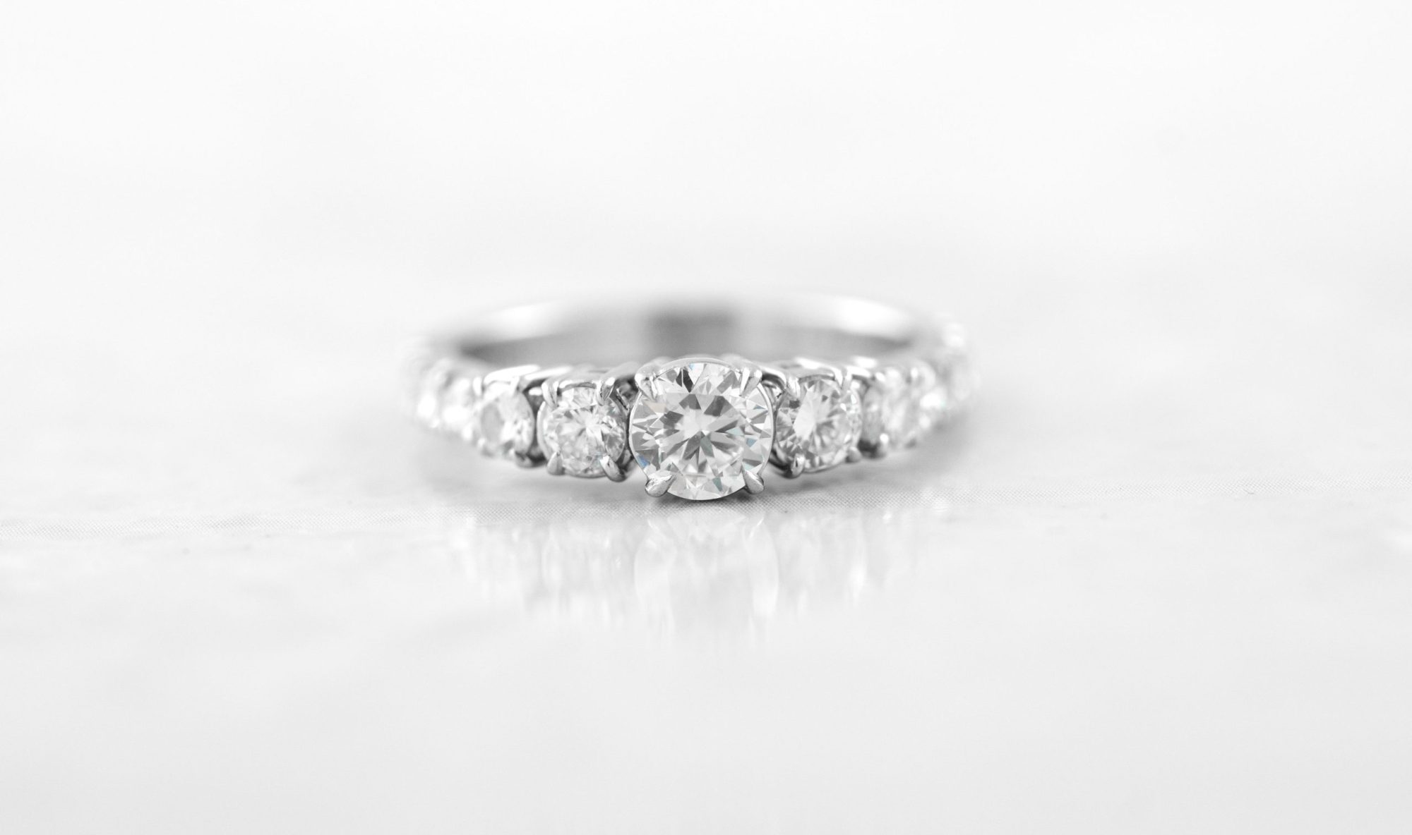 Diamond engagement ring with a round-cut center stone and a graduated diamond band set in white gold.