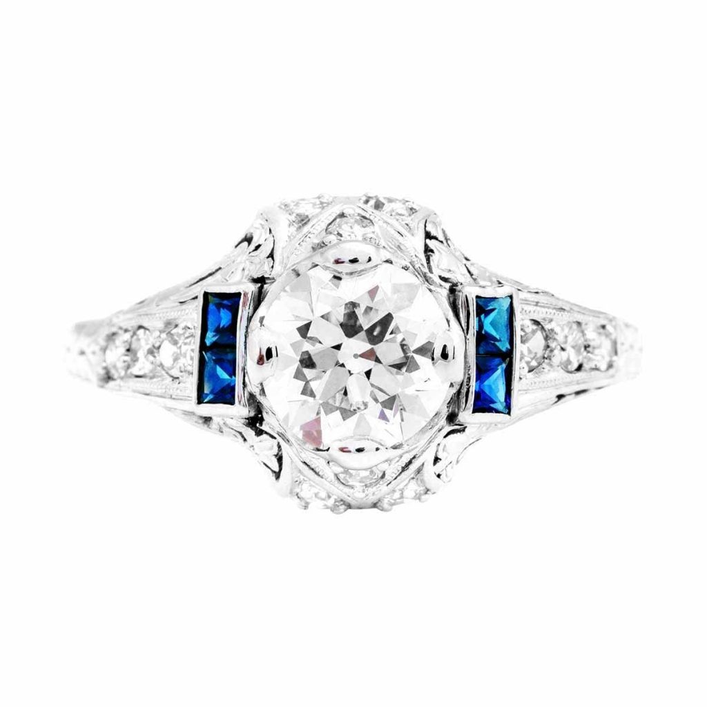 White gold Art Deco diamond engagement ring surrounded by blue sapphires and diamonds.