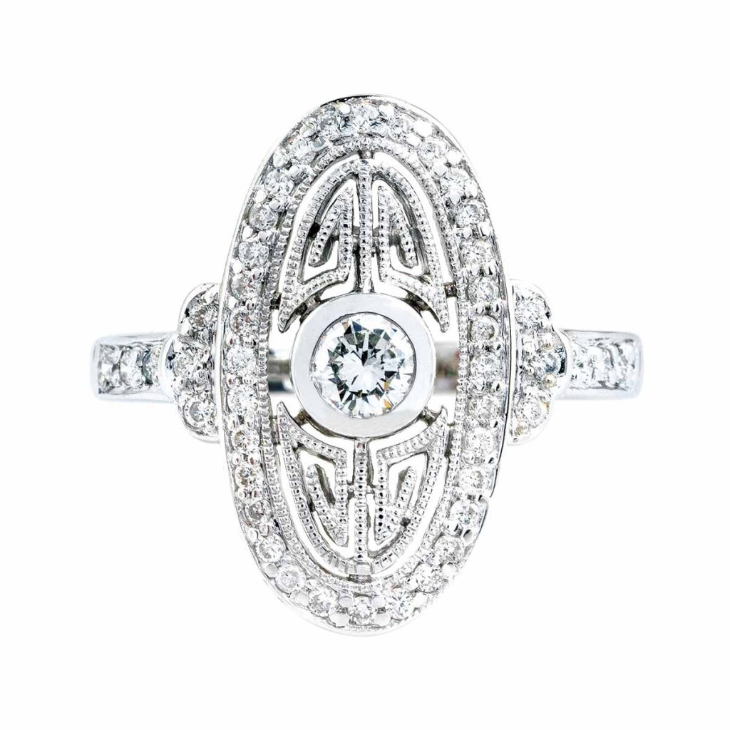 Vintage-inspired diamond ring with an intricate oval-shaped design, featuring a bezel-set center stone and pavé diamonds in white gold.