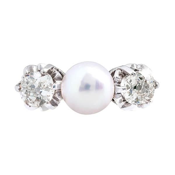 Antique platinum three-stone ring set with a white pearl and diamond side stones.