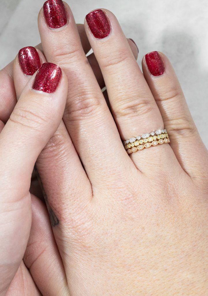 Woman wearing three stackable diamond rings in various metals.