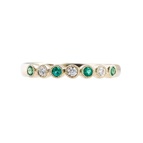 An elegant emerald and diamond eternity band showcasing a continuous circle of vibrant gemstones and sparkling diamonds.