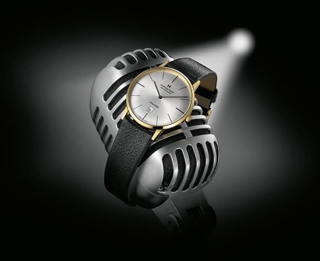 Pre-owned Hamilton watch in yellow gold with a black leather strap wrapped around a
retro microphone.