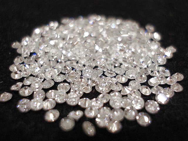 Pile of loose cut diamonds on a black background.