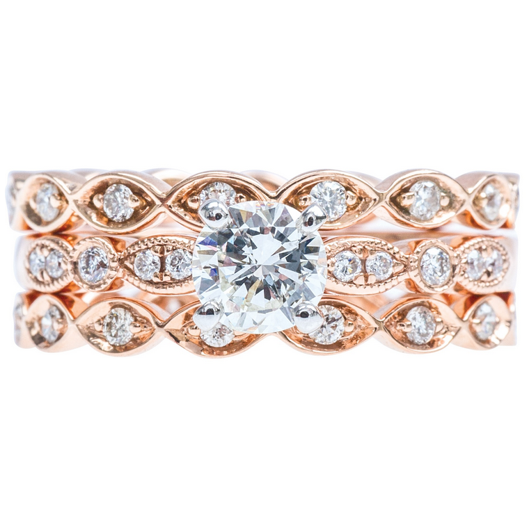 Rose gold three-row wedding set centered with a diamond surrounded by diamonds in the
bands.