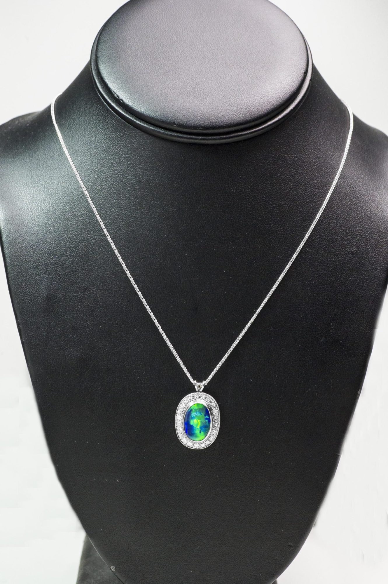 White gold necklace centered with a black opal surrounded by a diamond halo.