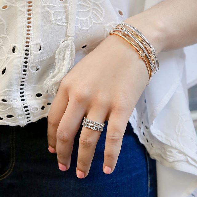 Woman’s hand featuring yellow, rose, and white gold diamond bangle and three stacking
diamond rings.