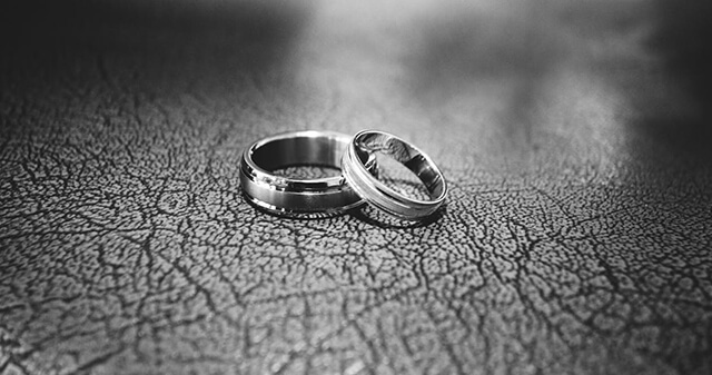 Two white gold men’s wedding bands on a gray table.