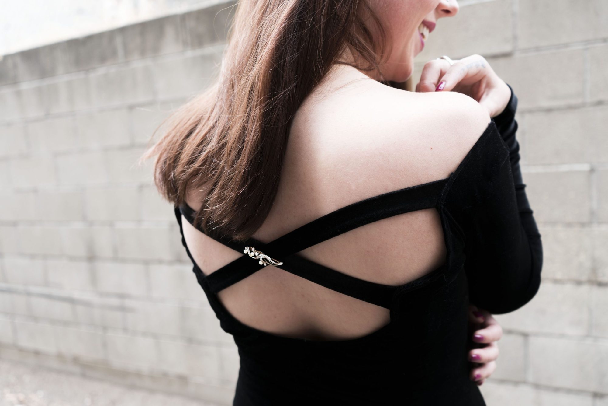 Woman wearing strappy-backed shirt with a brooch attached.