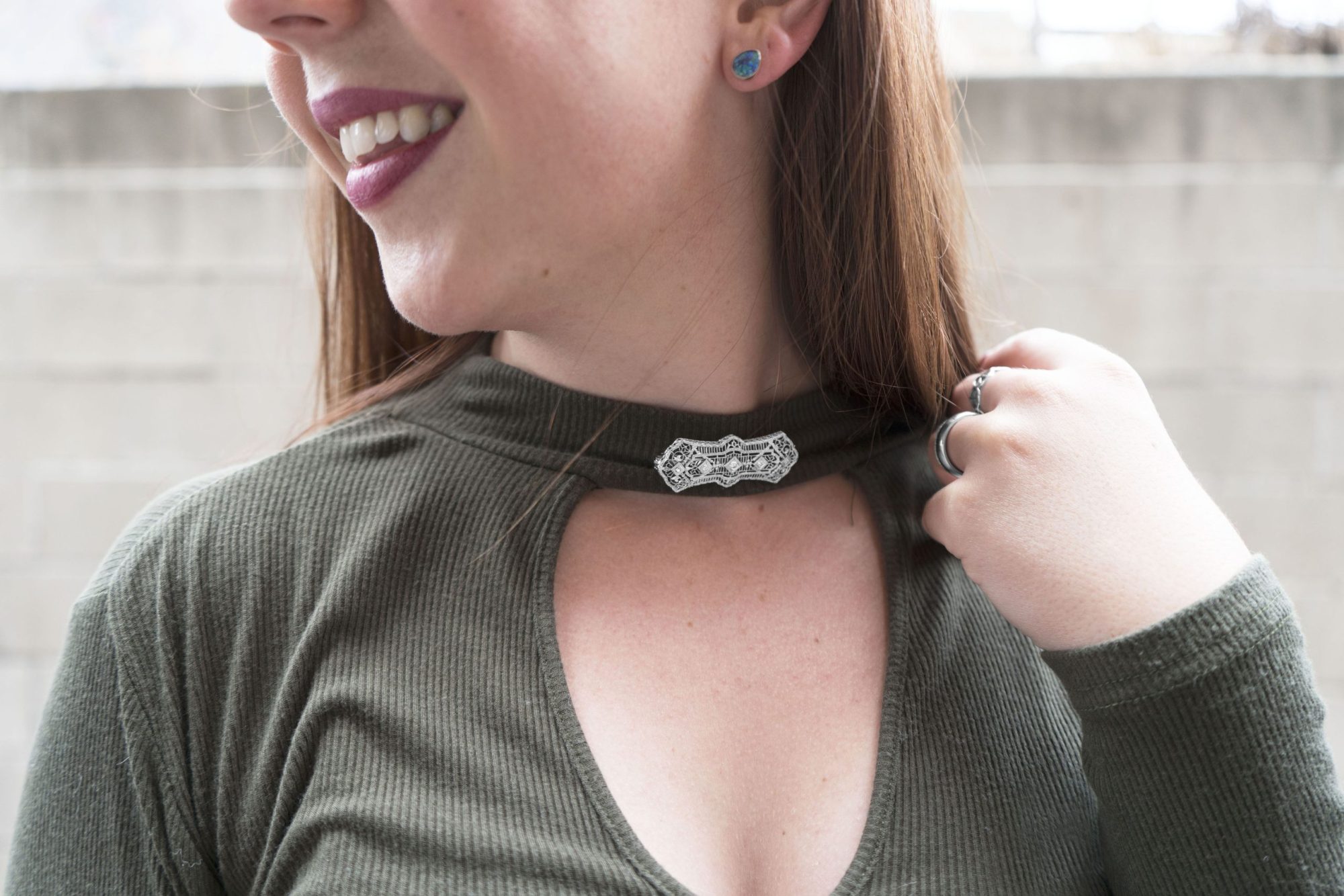 Woman wearing a silver brooch on the collar of her shirt.