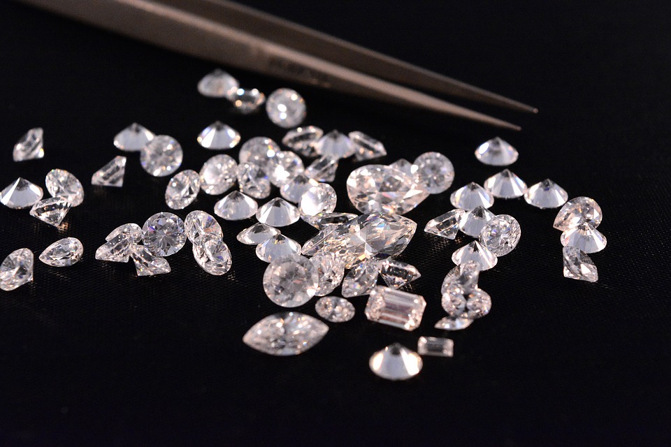 Loose round cut diamonds with tweezers on black background.