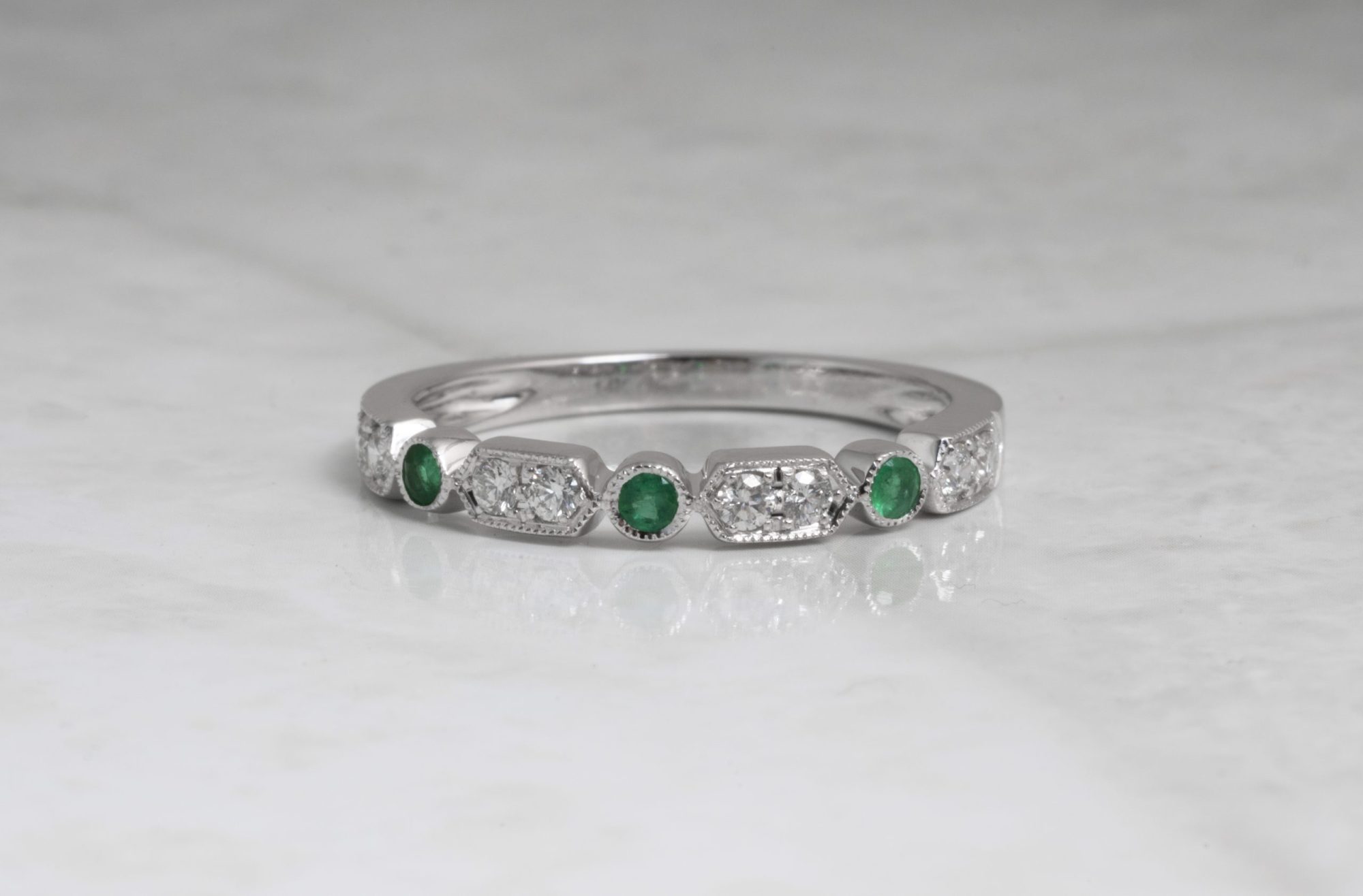 White gold wedding band set with diamonds and emeralds.