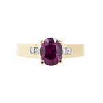 Yellow gold ring centered with an oval garnet and diamond side stones.