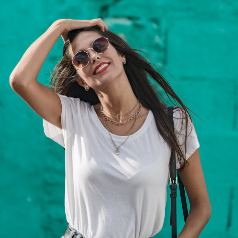 Woman wearing layered necklaces and sunglasses.