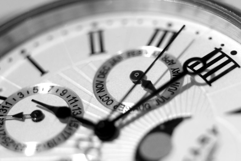 Close-up of a white watch dial with roman numeral markers.