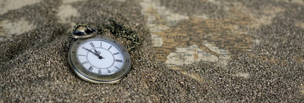 Antique roman numeral pocket watch in sand.