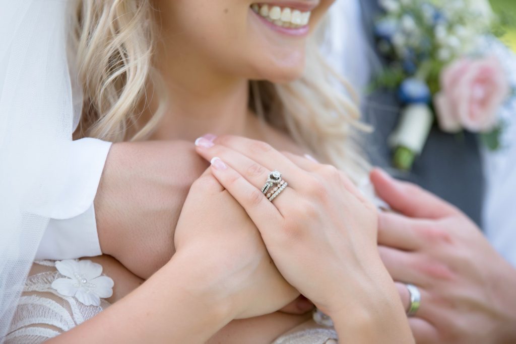 Woman’s hand featuring two diamond stacking rings and a diamond wedding set.