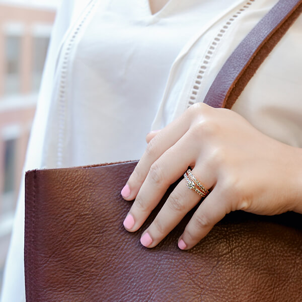 Woman’s hand holding bag showing off her diamond engagement ring.