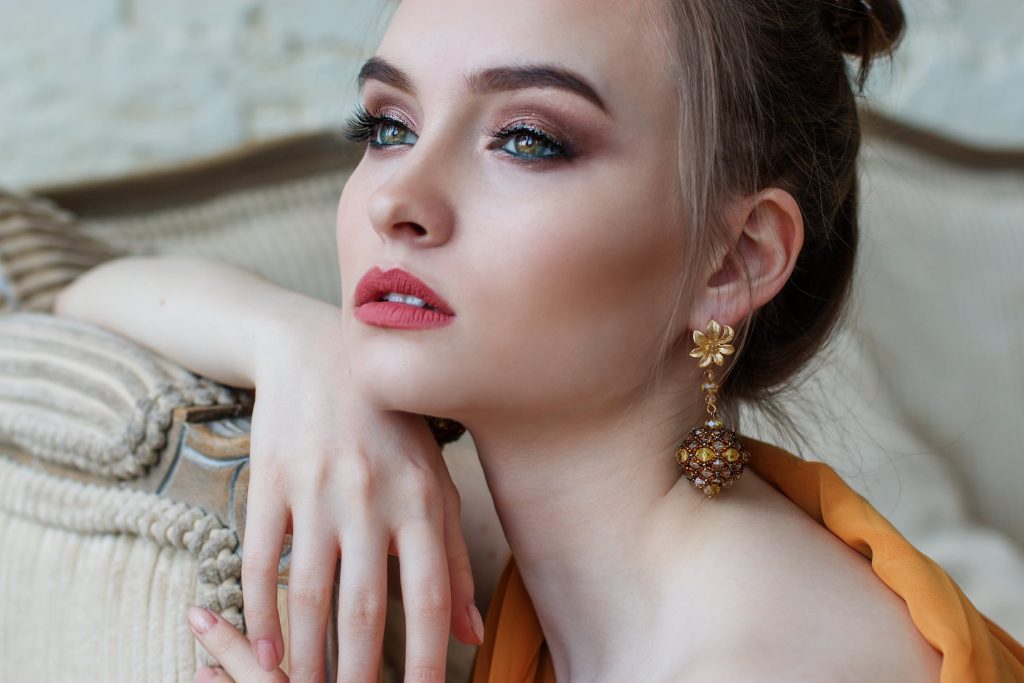 Woman wearing yellow gold floral drop earrings.