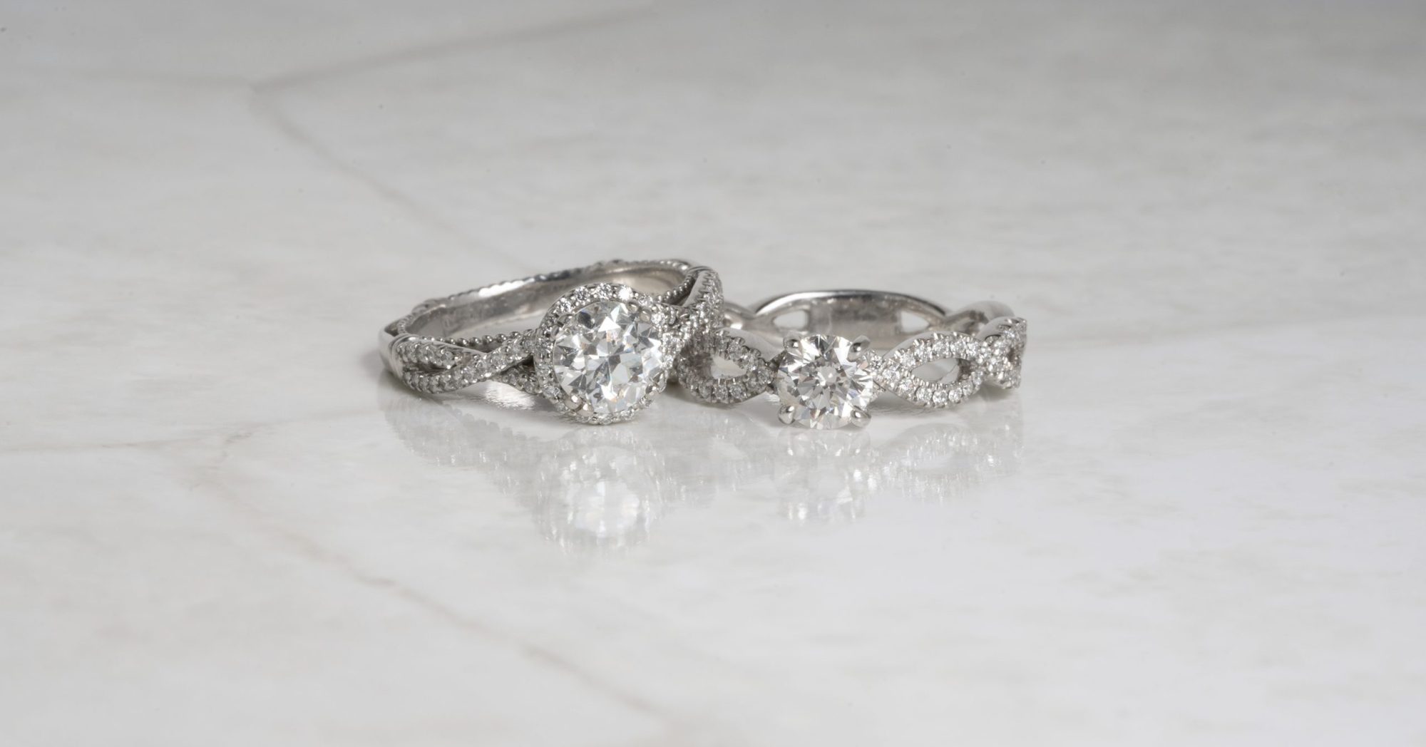 Two white gold diamond engagement rings with twisted bands.